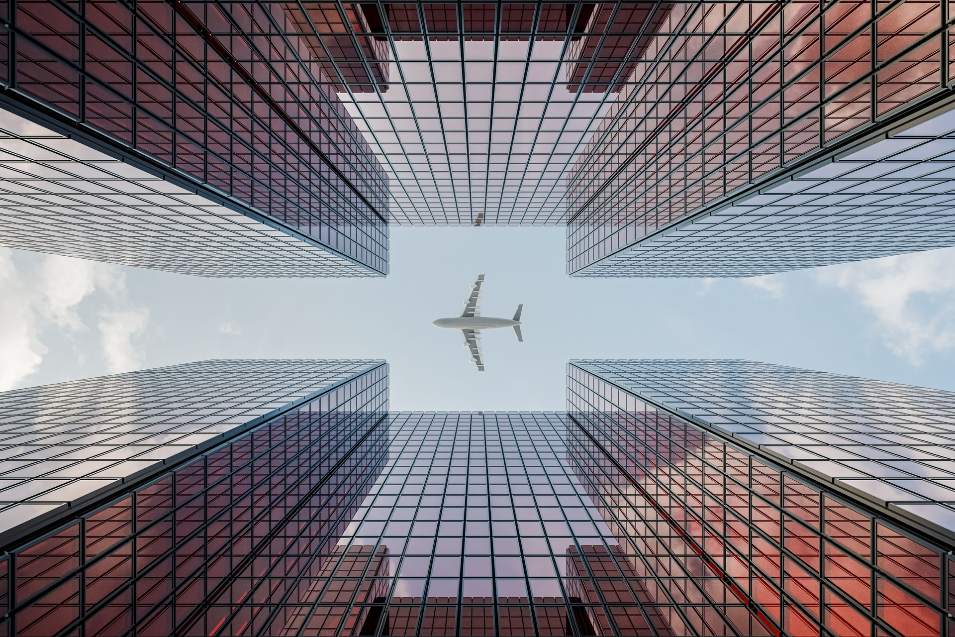 Skyscraper with Glass Curtain Wall, Reflecting Sky and Clouds, as an Airplane Passes By